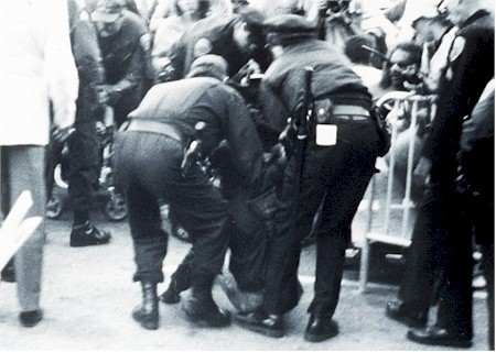 Police arrest a demonstrator. Description follows.